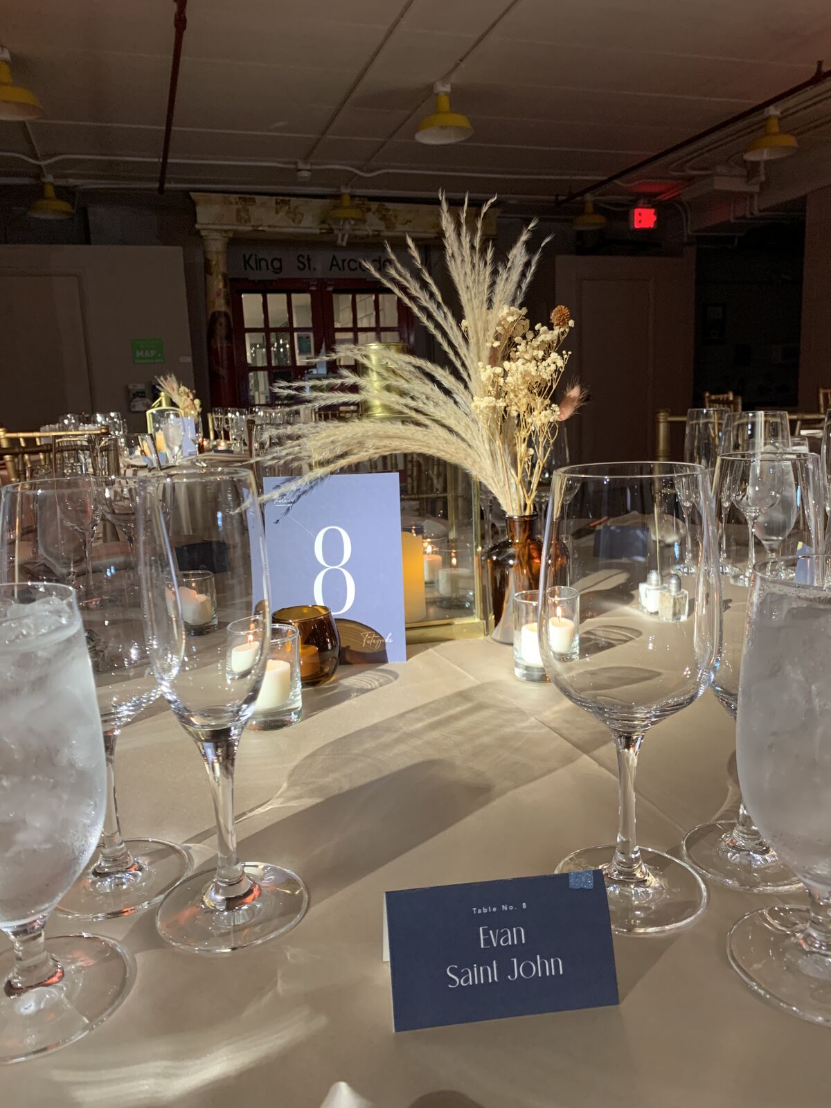 Industrial-chic reception place setting with pampas, candles and a printed place card
