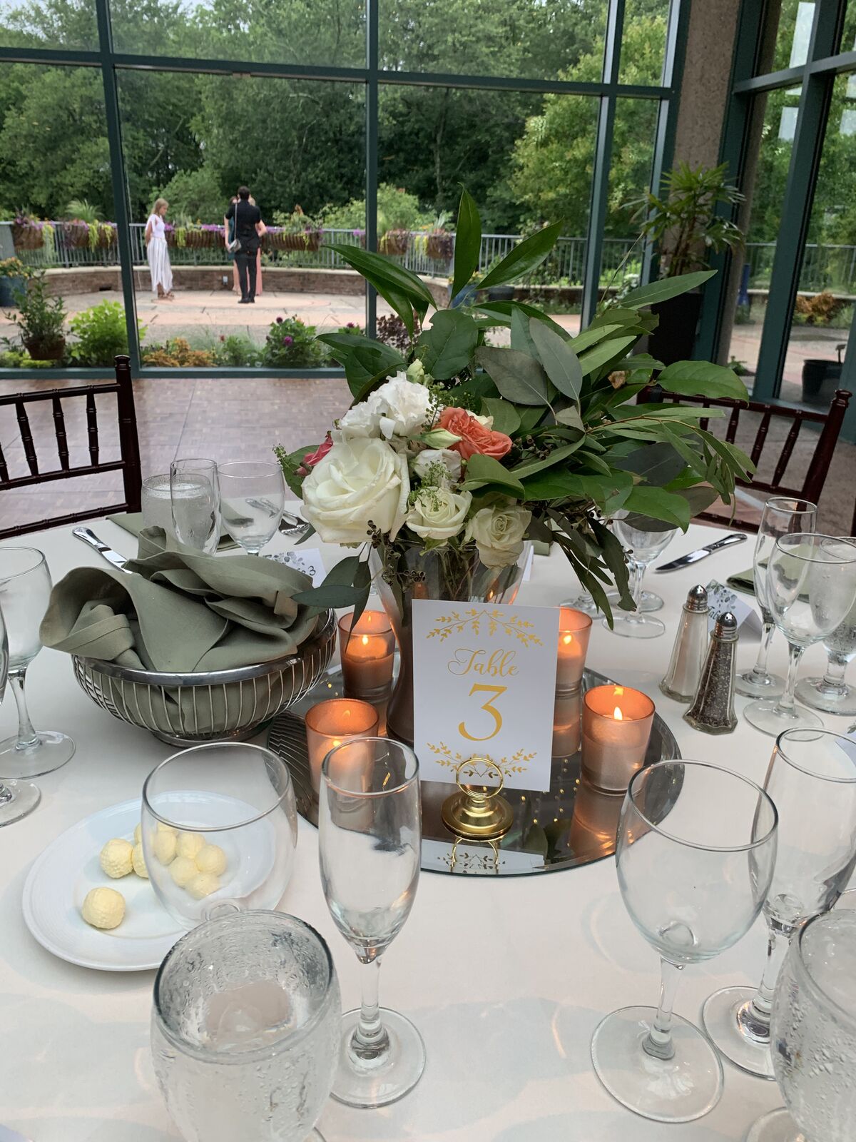 Botanical garden reception tablescape with candles, greenery napkins and gold table number