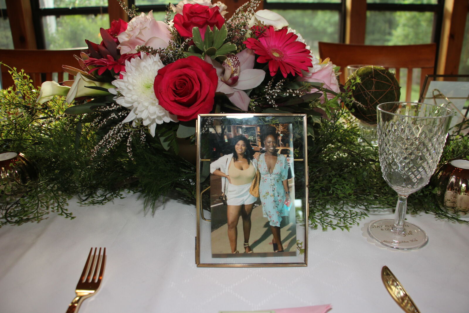 Floral centerpiece with a framed photo detail on a greenery-draped table