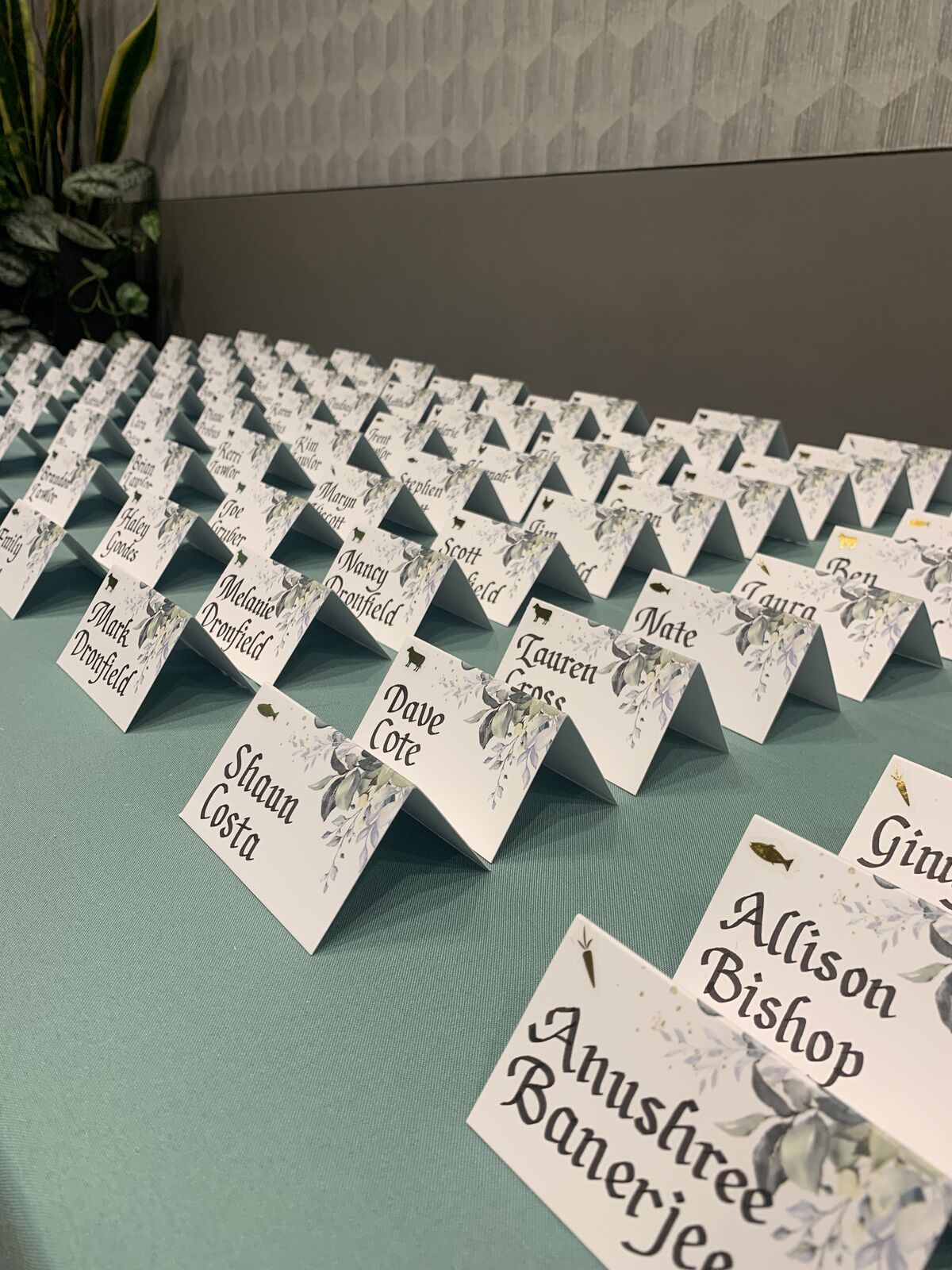 Hand-lettered escort cards arrayed on a sage table runner
