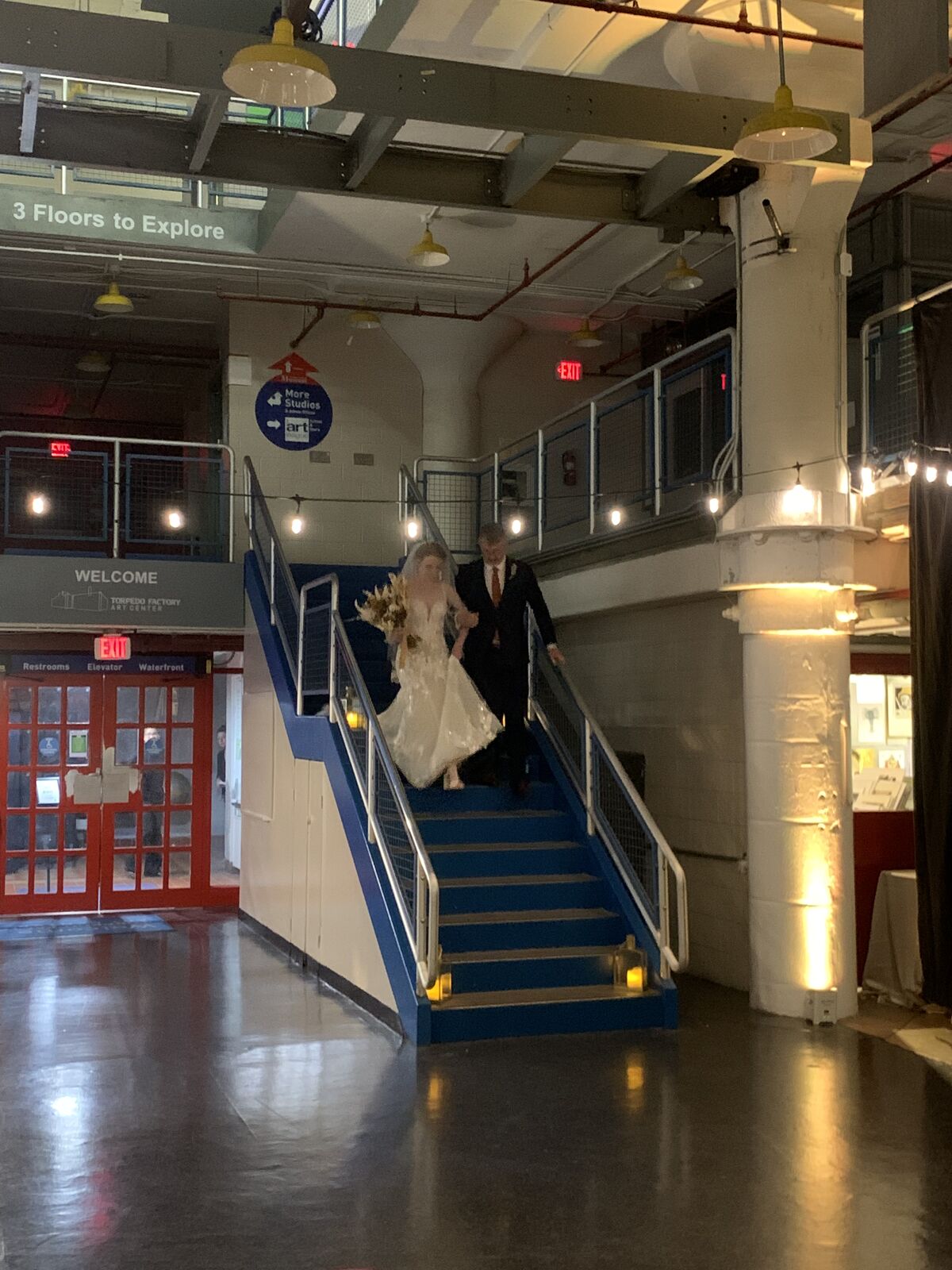 Bride at the top of a grand staircase in an industrial gallery venue