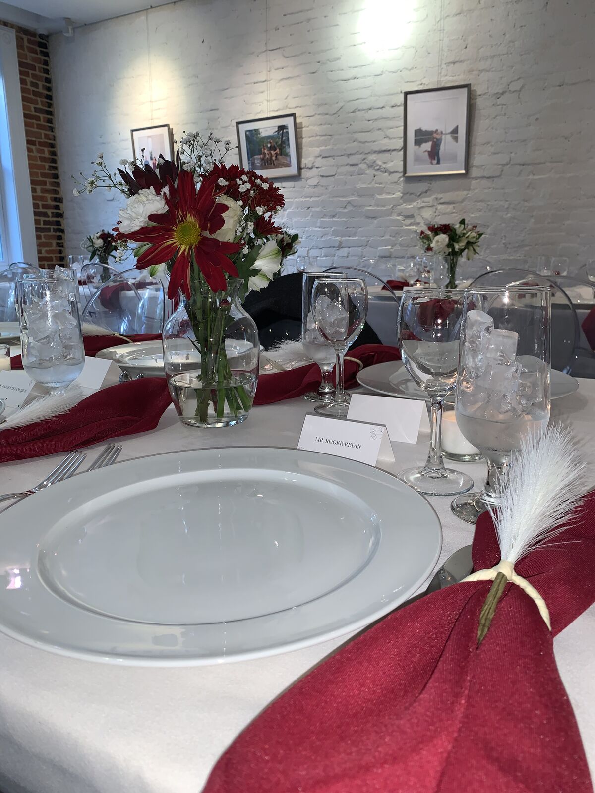 Intimate dinner place setting with burgundy napkins against white brick