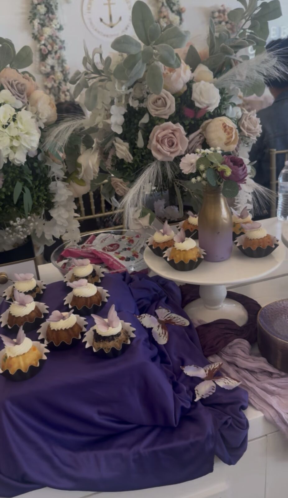 Butterfly-topped mini bundt cakes on a purple-draped dessert table
